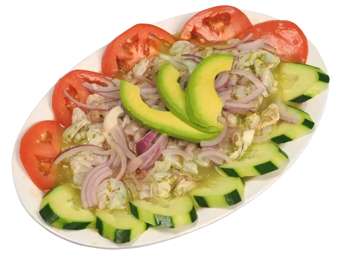 Colorful shrimp aguachile verde with tomatoes, cucumbers, and onions on a white plate.