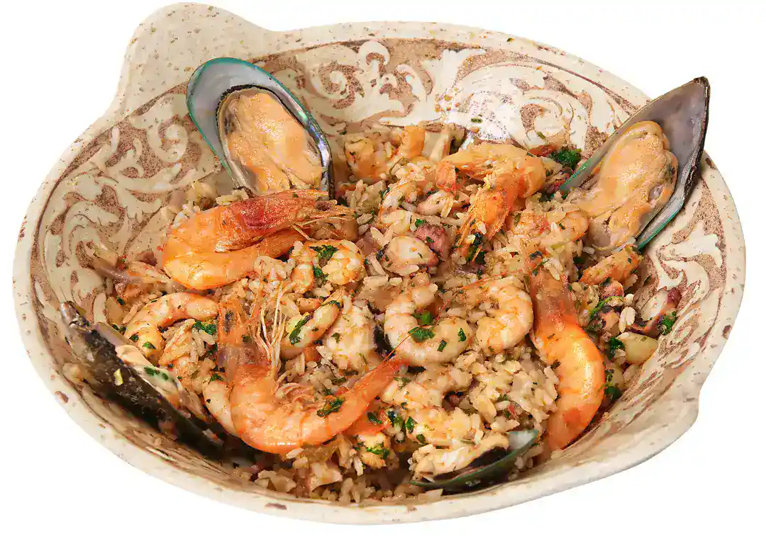 Seafood paella with shrimp, mussels, and rice in a decorative bowl.