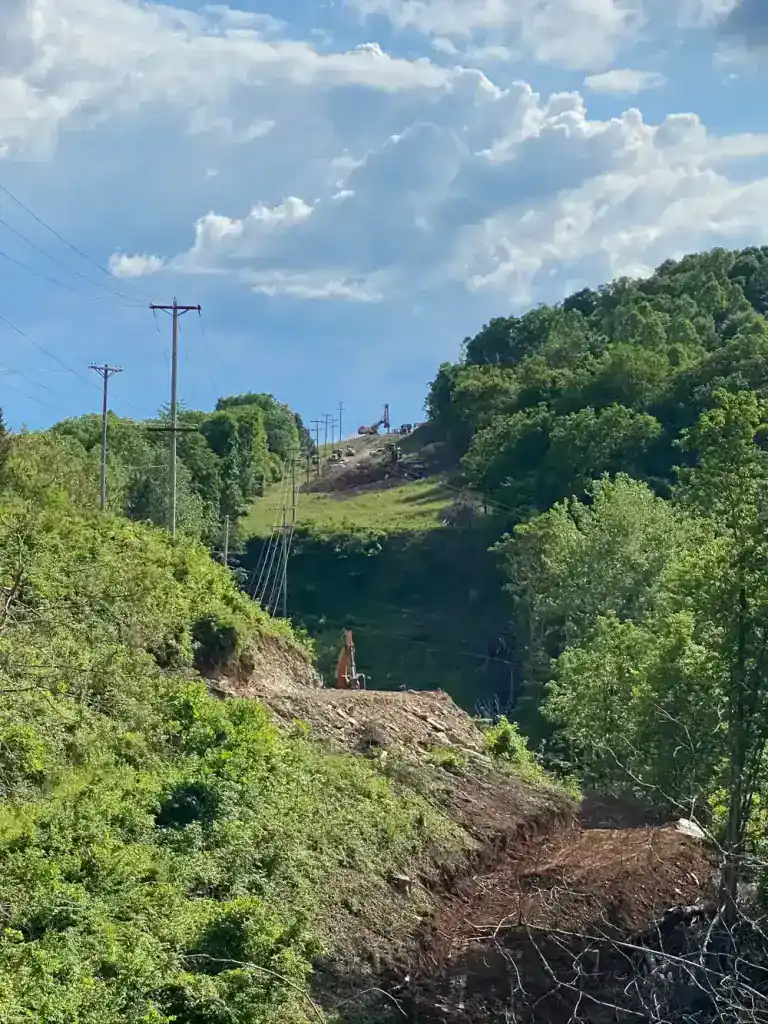 High-voltage transmission towers crossing lush green hills in Southern Ohio.