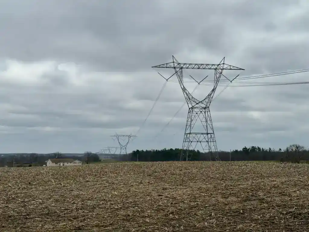 Damaged power lines and towers in open field following storm destruction.