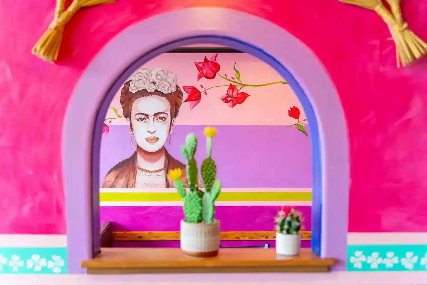 Vibrant Mexican-themed wall art with cacti and a portrait.