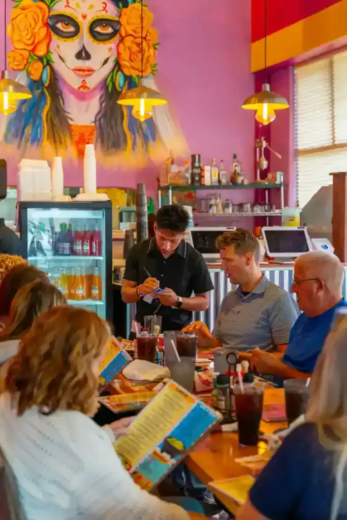 Vibrant Mexican restaurant interior with colorful decor and patrons enjoying meals.