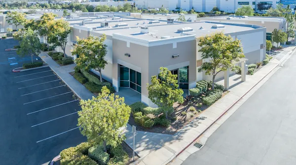 A welcoming, modern single-story building with large windows, thoughtfully landscaped greenery, and a spacious parking lot—showcasing Fetch‑A‑Tech’s commitment to comfort and helpful service in Las Vegas on a bright, sunny day.