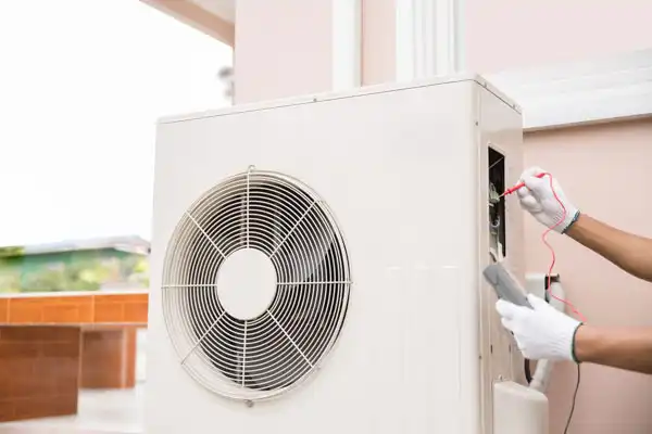 A friendly technician in white gloves uses a multimeter to carefully inspect the electrical components of an outdoor air conditioning unit, ensuring reliable comfort for a Las Vegas home. This reflects Fetch‑A‑Tech’s honest, family-owned commitment to helpful service and keeping local families cool.