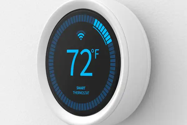 A round smart thermostat set to a comfortable 72 degrees Fahrenheit glows with a blue digital display and Wi-Fi symbol, mounted on a clean white wall. Installed by Fetch‑A‑Tech’s trusted, family-owned team in Las Vegas, this smart thermostat helps create a cozy and energy-efficient home environment for local families.