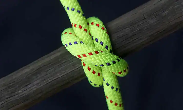 Bright yellow climbing rope with red and blue accents tied to a wooden beam.