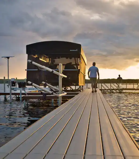 Relaxing scene at Hall's Sport Center marina with a person walking on the dock during sunset.