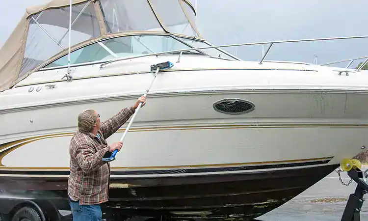 A man cleaning a large luxury boat at Hall's Sport Center boat service.