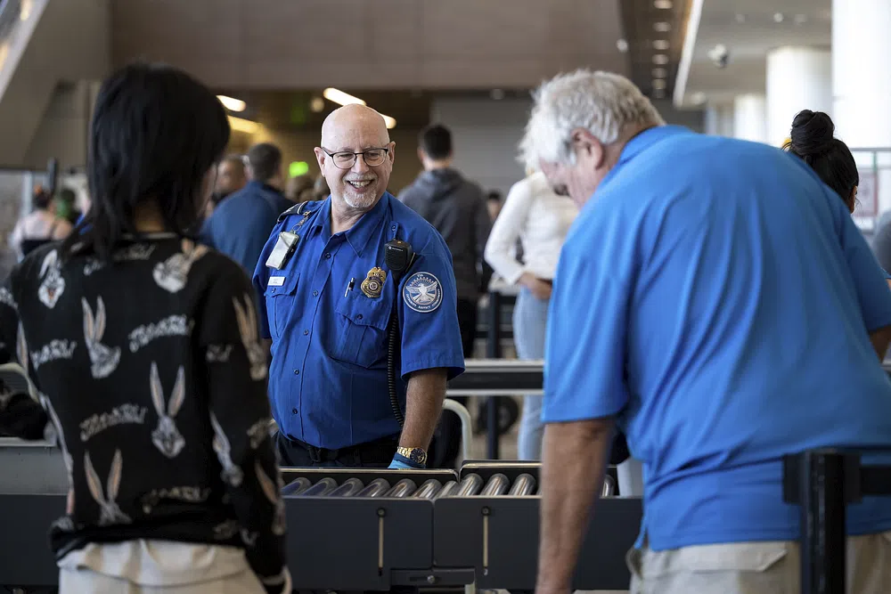 A smiling TSA agent at the airport TSA PreCheck checkpoint