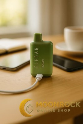 Elf Bar BC5000 disposable vape charging via USB-C on a desk with phone and coffee, Moonrock Online Shop logo watermark