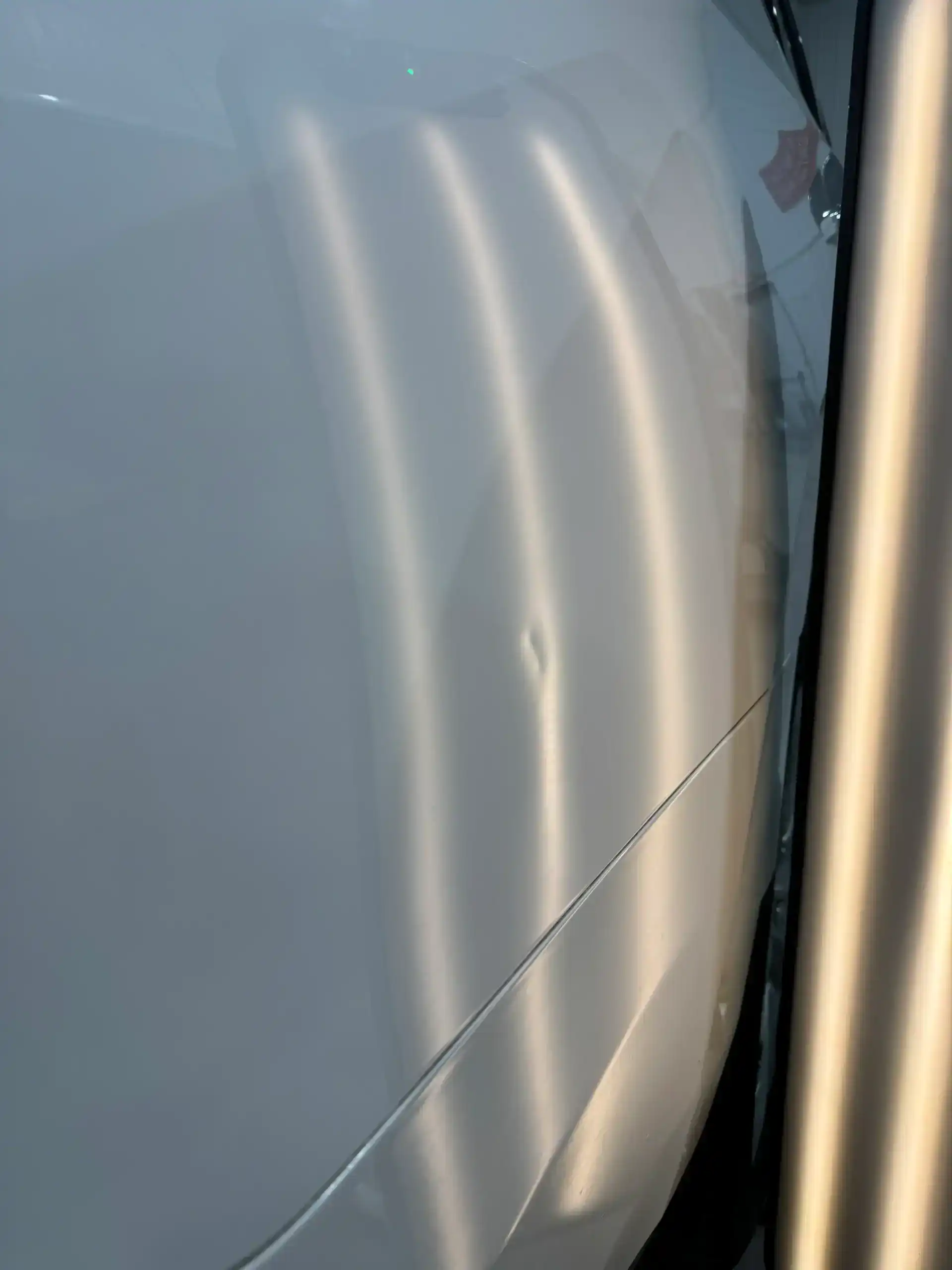 Close-up of car body with reflections and minor dent.