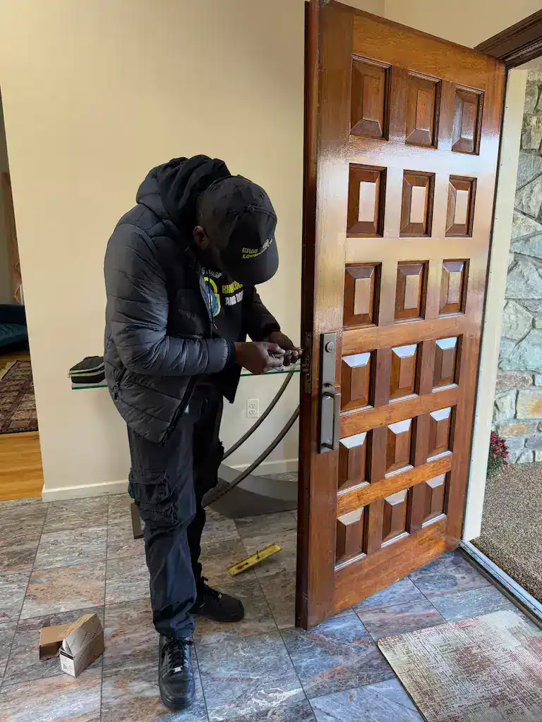 Residential locksmith installing a new lock on a wooden front door in Jessup Maryland home