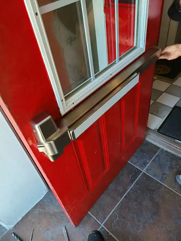 Commercial locksmith installing a panic bar exit device on a business door in Greenbelt, Maryland to support safe and compliant access.