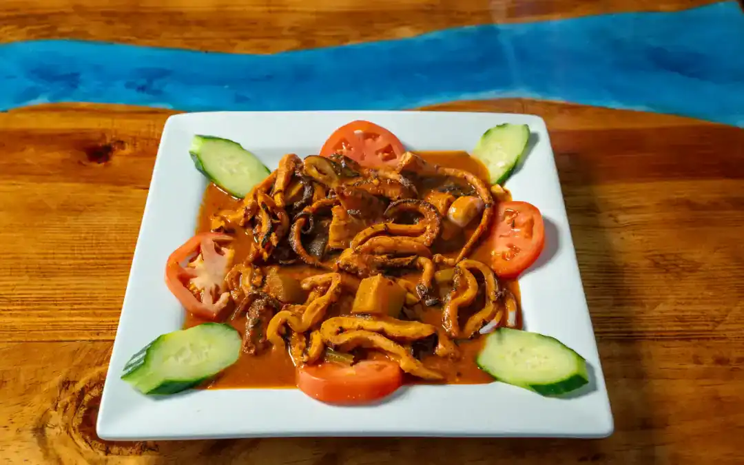 Pulpo Enojado seafood dish with vegetables on a white plate.