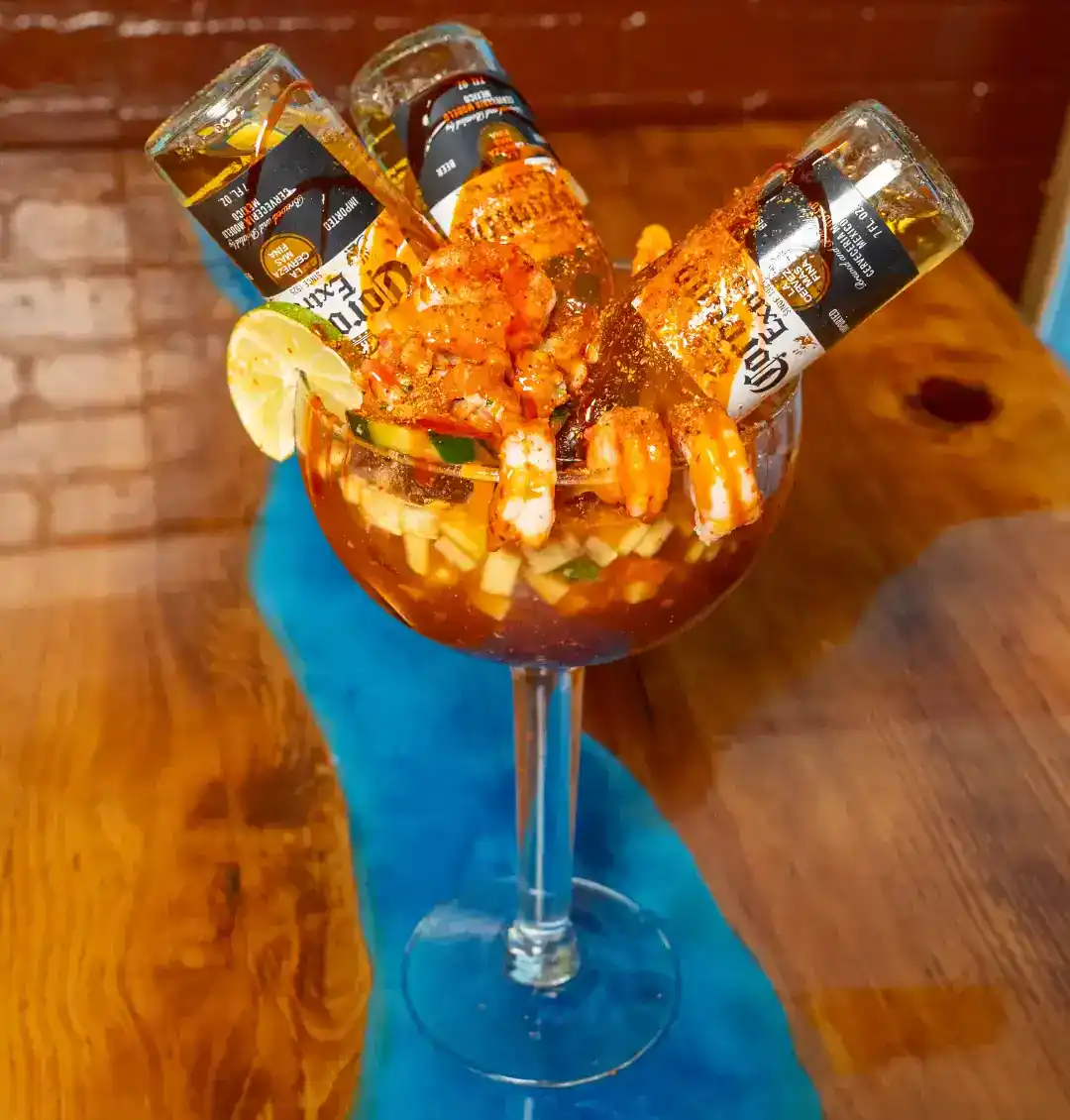Seafood cocktail with beer bottles and lemon slice in a glass.