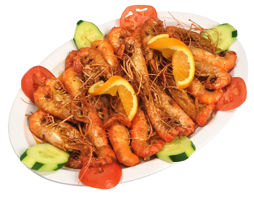 Delicious cooked langostinos garnished with lemon slices and fresh vegetables.