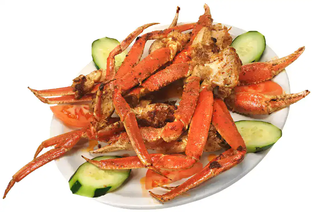 Delicious cooked crab legs served with cucumber slices on a white plate.