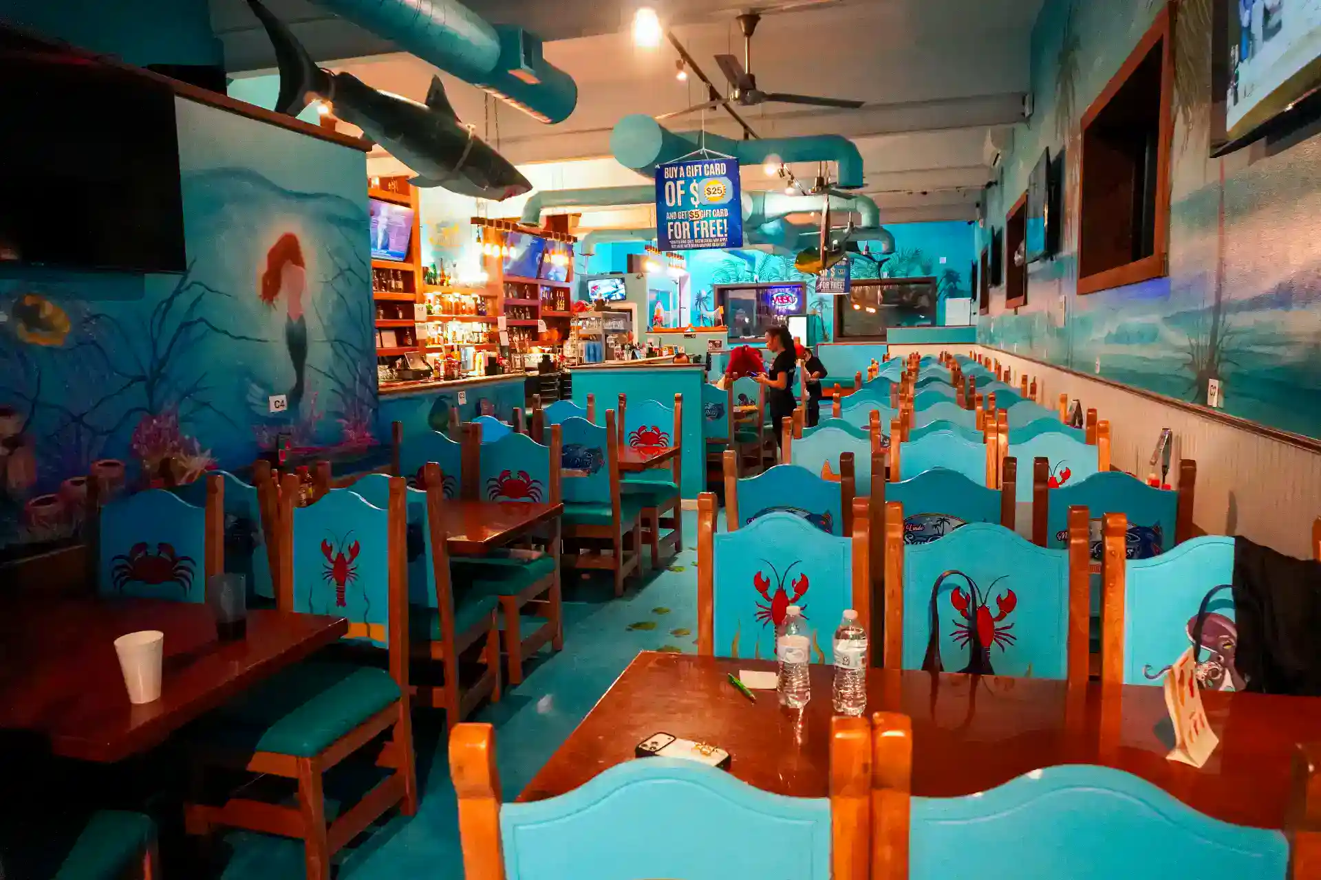 Colorful restaurant interior with ocean-themed decor and blue chairs.