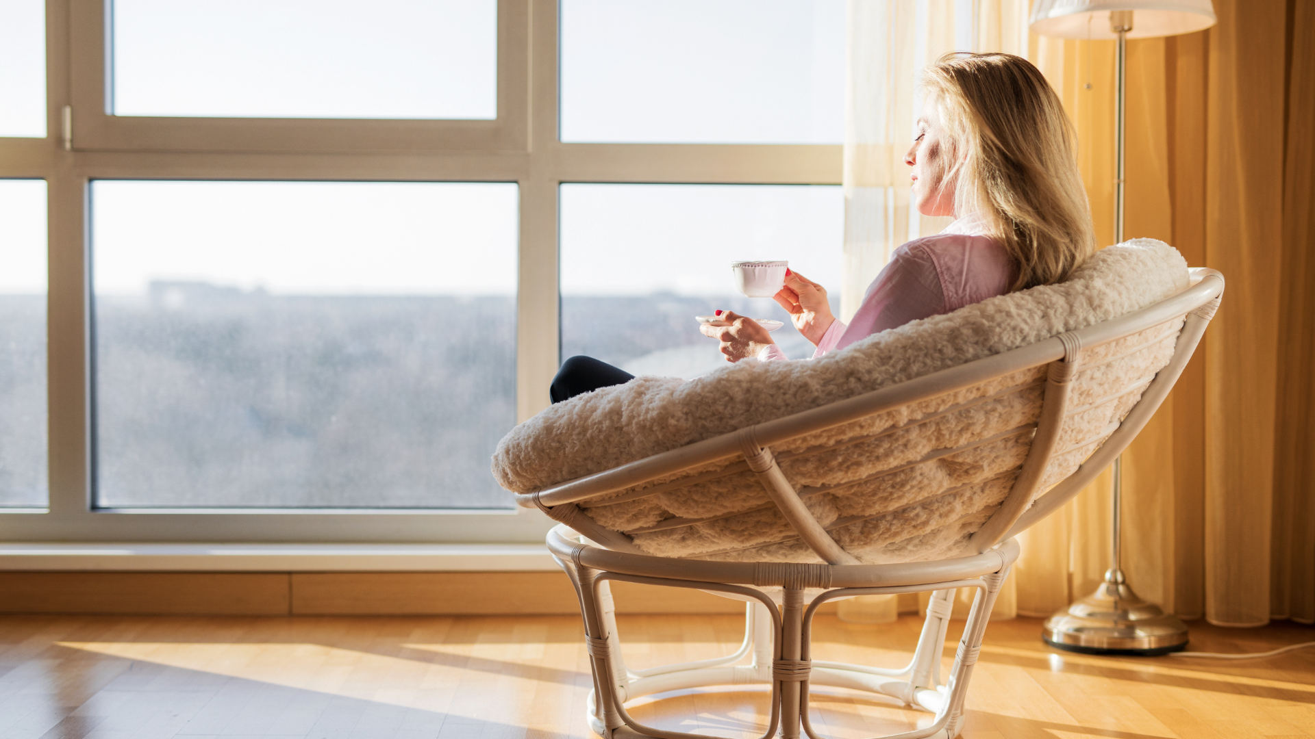 A woman practicing herbal tea break and window gazing as part of her self-care during her lunch break