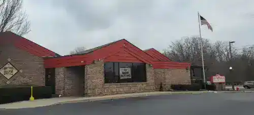 Exterior view of a building with a red roof and brick walls, featuring a "Rename Website" sign, unde.
