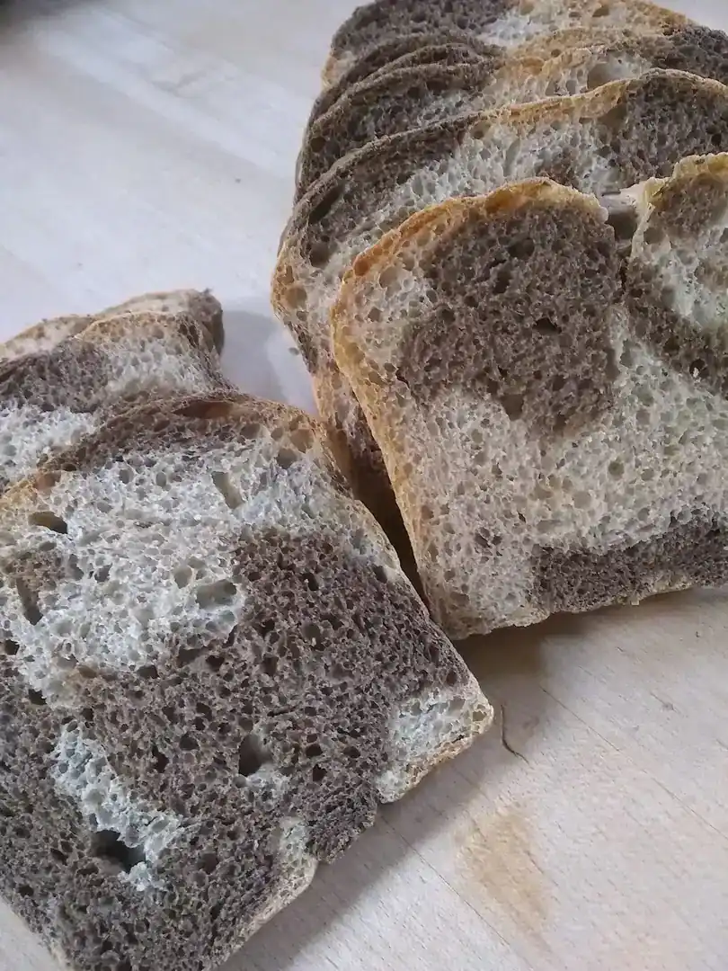 Freshly sliced whole grain bread on a wooden surface, showcasing its texture and crust.