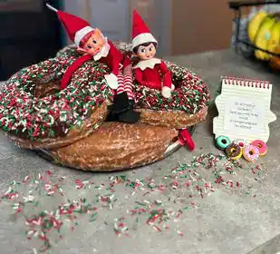 Festive Christmas doughnuts with elf dolls and sprinkles for holiday celebration.