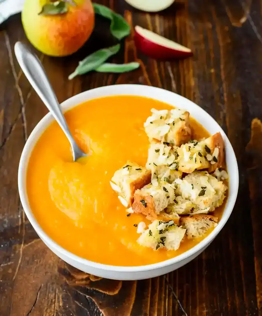 Delicious butternut squash soup with crunchy croutons in a white bowl.