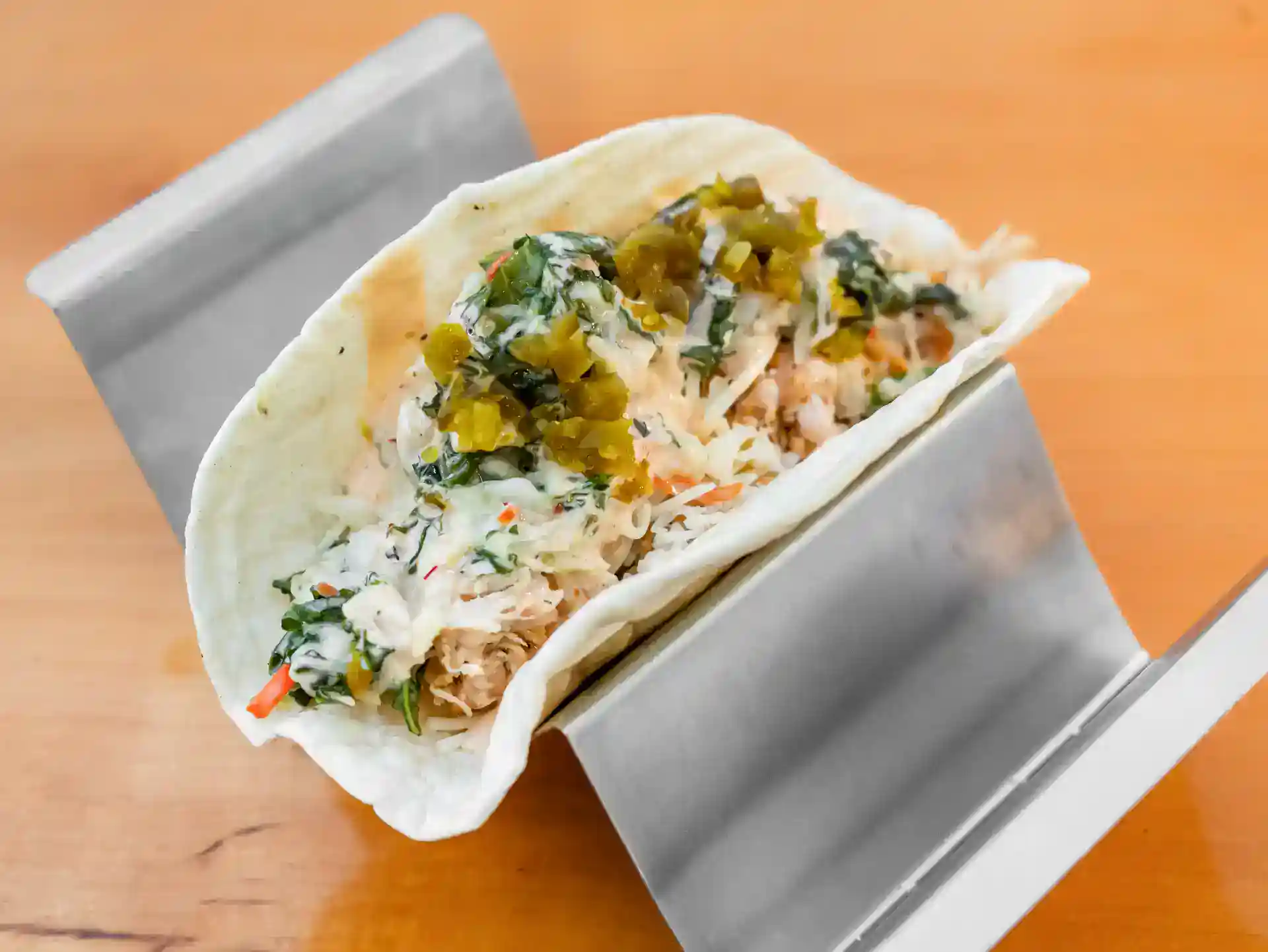 Tasty fish taco with fresh vegetables and pickles on a soft tortilla.