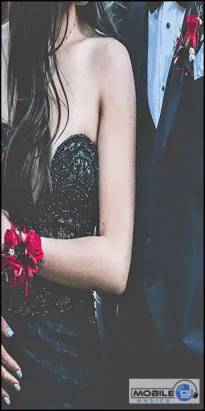 Elegant woman in black dress with red floral wrist corsage at formal event.