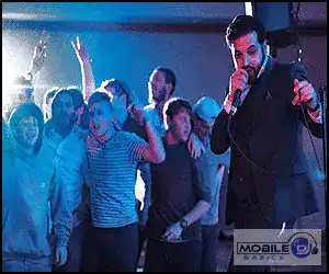 DJ performing at a lively party with dancing crowd and colorful lighting.