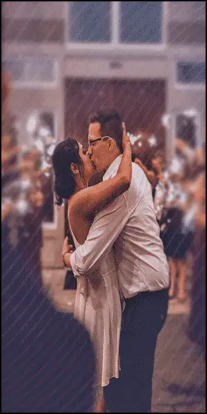 Couple sharing a romantic kiss at a lively outdoor event.