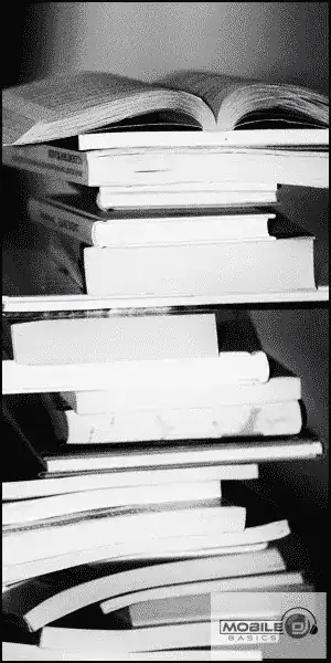 Stack of books with one open on top, black and white image.