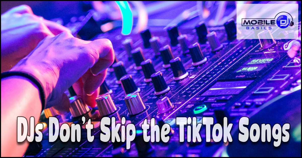 A DJ scrolls a phone for trending TikTok songs beside a controller and laptop, finding new viral hits to add to a set.