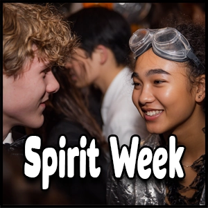 Two teenagers in costumes smile at each other at a crowded event, showcasing the excitement of school spirit activities. The words “Spirit Week” are in large white text over the image.