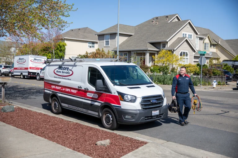 A Moore Home Services van is parked on a quiet residential street as one of our trusted technicians heads toward a home, fully equipped and ready to provide expert plumbing repair. Count on us for reliable service, clean workmanship, and the peace of mind that comes with our satisfaction guarantees—your comfort is always our top priority.