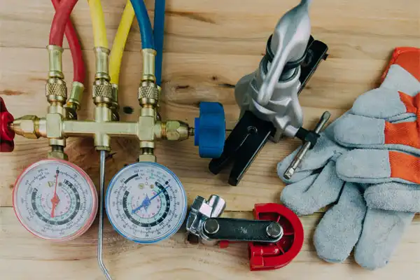 HVAC and plumbing tools neatly arranged on a clean wooden surface, featuring a manifold gauge, pipe cutter, gloves, and specialized drain service equipment—reflecting Moore Home Services’ commitment to expert care, spotless workmanship, and trustworthy service you can count on every time.