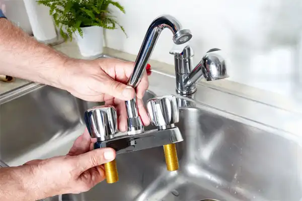 A Moore Home Services expert installs a new two-handle kitchen faucet with durable brass fittings above a spotless stainless steel sink. Our trusted team guarantees precise, mess-free plumbing service—so you can always count on clean water and total peace of mind.
