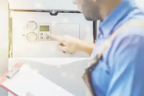 A friendly Moore Home Services technician, dressed in clean work attire, expertly adjusts your wall-mounted control panel while reviewing details on a clipboard. Trust our HVAC and plumbing professionals to provide reliable service backed by our guarantees—ensuring your home stays comfortable, efficient, and spotless after every visit.