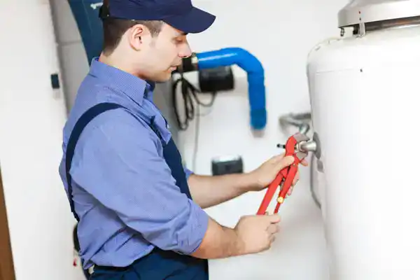 A Moore Home Services technician, in professional uniform, expertly uses a pipe wrench to service a home water heater. Count on our trusted plumbing team for top-quality repairs—always clean, courteous, and backed by our satisfaction guarantee.