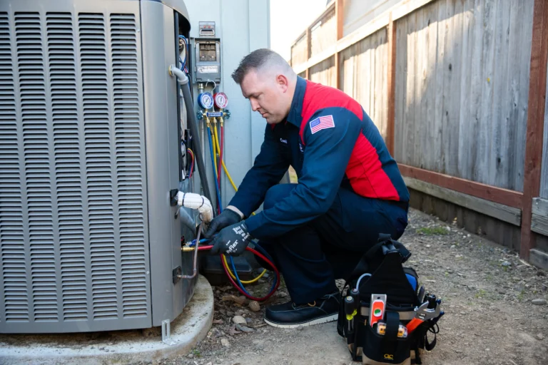 A friendly Moore Home Services technician, dressed in a clean uniform, expertly services an outdoor HVAC unit using professional tools and gauges. His organized tool bag sits nearby, reflecting our commitment to tidy workspaces and reliable service. Trust Moore Home Services for dependable HVAC repairs, backed by our satisfaction guarantees and always-clean approach.