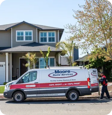 A Moore Home Services van is parked on a quiet residential street in front of a welcoming home, as one of our friendly, uniformed technicians walks toward the sidewalk—ready to deliver expert HVAC, plumbing, or drain service. Count on Moore for clean workspaces, trusted solutions, and industry-leading guarantees every time we visit.