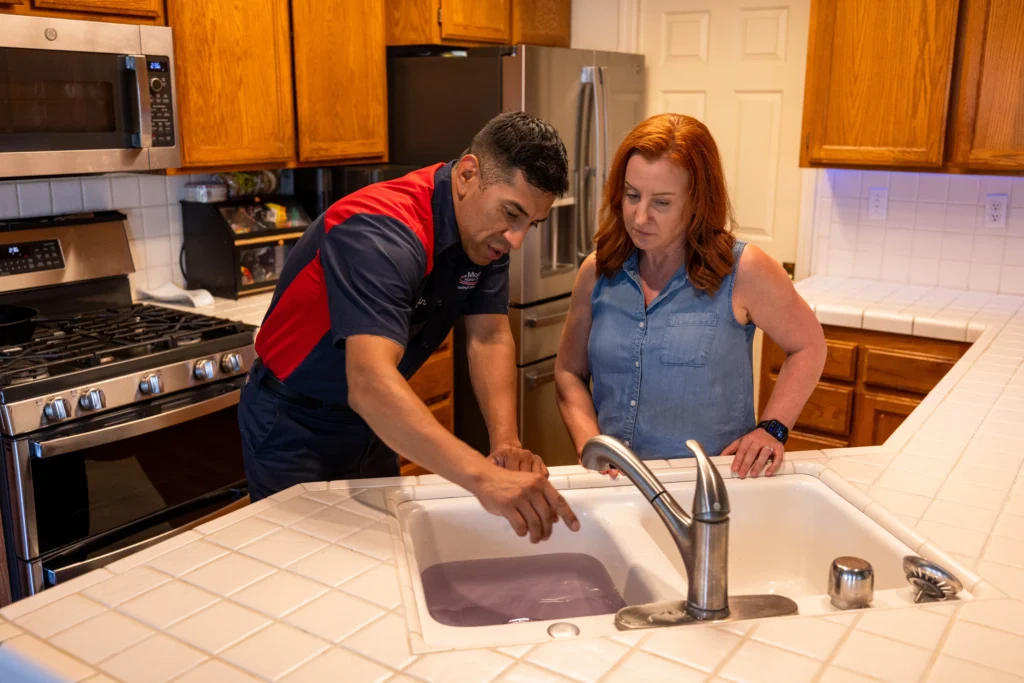 Our friendly technician reviews a kitchen drain concern with a homeowner, ensuring clean, expert plumbing service you can trust.
