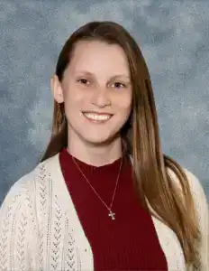 Smiling student at New Era Christian School in a red sweater and white cardigan.