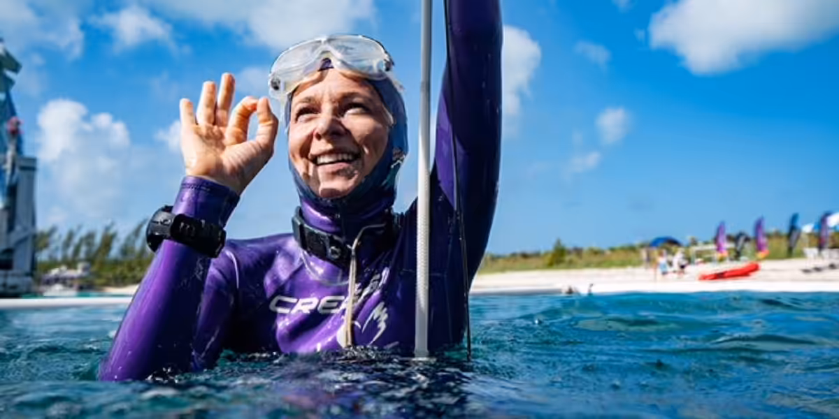 Femme en combinaison de plongée souriante, découvrant le monde sous-marin en toute sécurité.