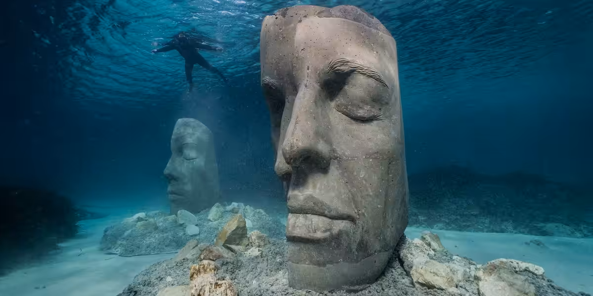 Sculptures sous-marines mystérieuses entourées d'une eau cristalline, explorées par un plongeur.