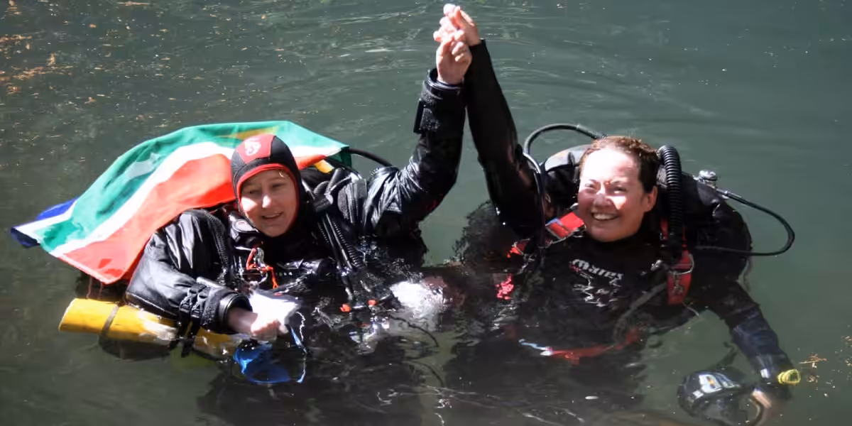 Deux plongeuses sous-marines s'amusent, vêtues de combinaisons de plongée. Exploration aquatique enrichissante.