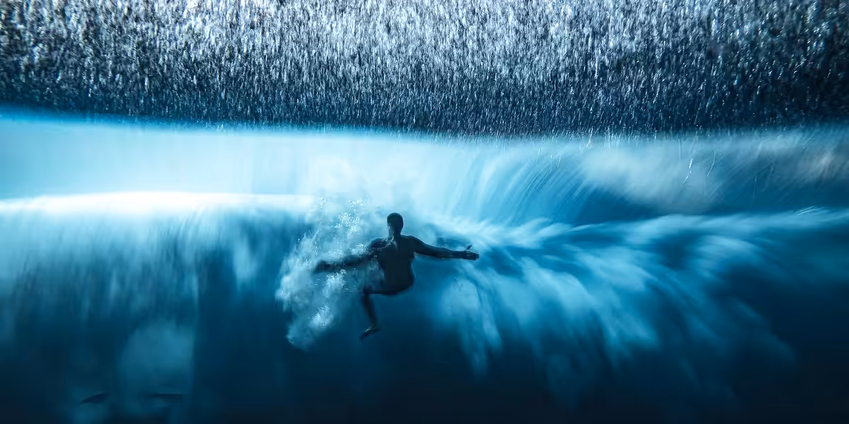 Surfeur plongeant dans une vague majestueuse, explorant les merveilles du monde sous-marin.