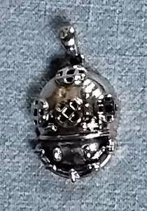 Un pendentif en forme de casque de scaphandrier évoque l'aventure sous-marine et l'exploration des profondeurs océaniques.