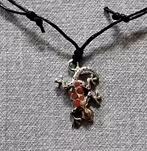 Un pendentif en forme de gecko sur un cordon noir évoque l'exotisme des récifs coralliens et l'aventure sous-marine.