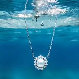 Un collier orné d'une perle flotte dans l'eau cristalline, évoquant la beauté sereine des profondeurs marines. #Océan